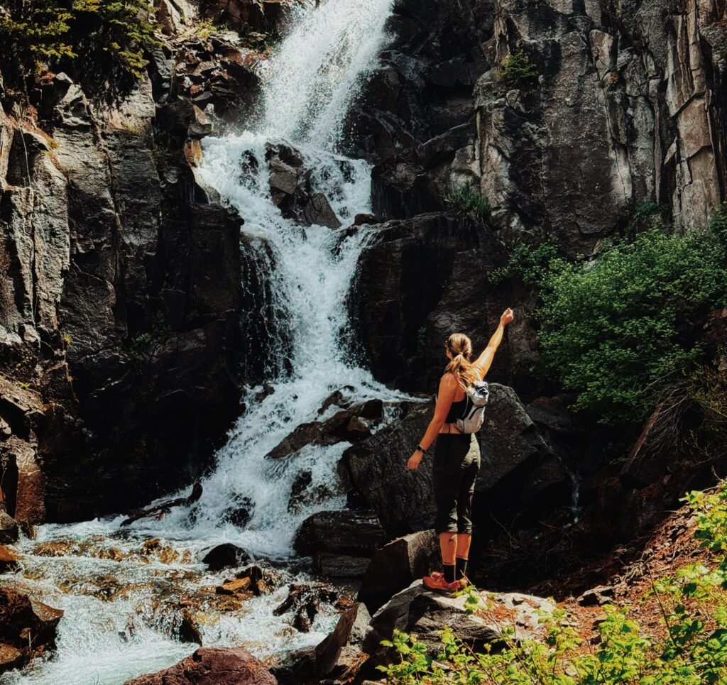 Hiker on Chief Ouray Hike in Ouray Colorado standing in front of a waterfall.